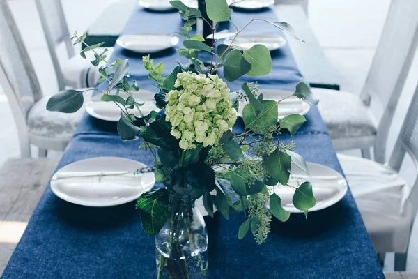 桌子上的绿色和白色花心花朵水平拍摄 配有蓝色桌布和白色盘子 — 图库照片