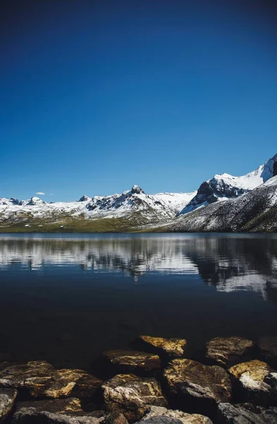 Sebuah Gambar Vertikal Air Dekat Pegunungan Bersalju Bawah Langit Biru — Stok Foto