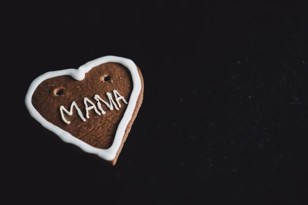 Plan rapproché d'un cookie avec maman écrit dessus sur une surface noire — Photo