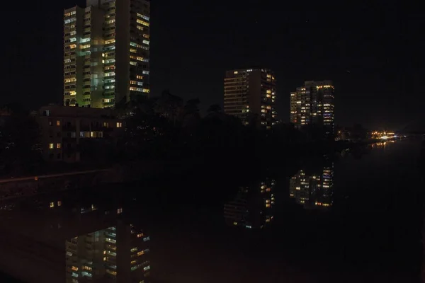 Tiro Horizontal Edifícios Altos Com Luzes Cercadas Por Árvores Noite — Fotografia de Stock