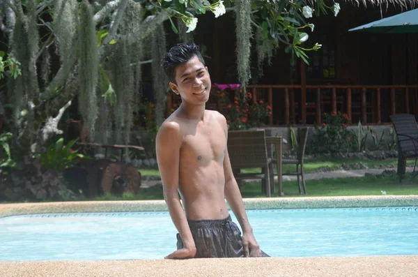 Smiling male wearing swimsuit standing inside of a pool — Stock Photo, Image