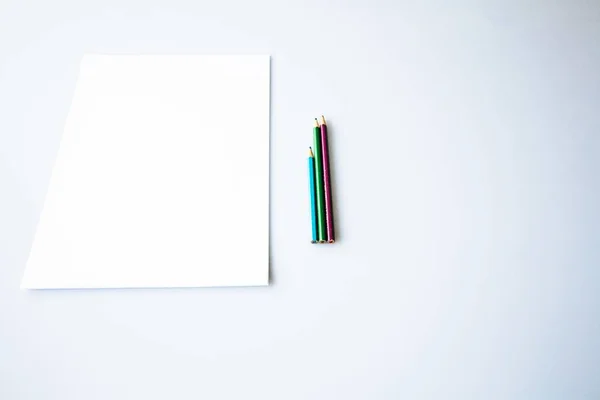 Beyaz bir yüzey üzerinde beyaz bir kağıt yakınındaki boyama kalemlerinin yukarıdan çekimleri — Stok fotoğraf