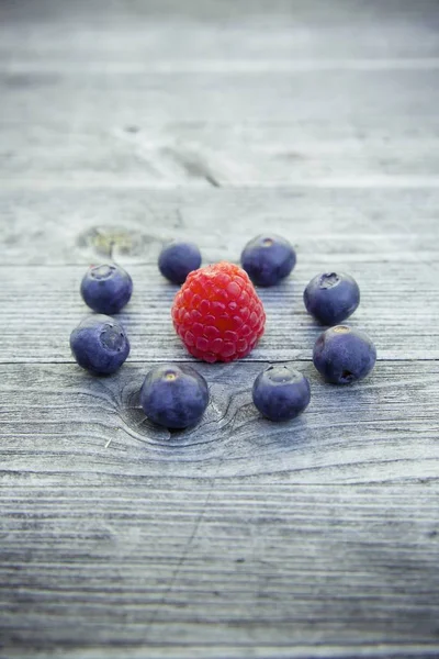 High angle shot of raspberry and blueberries on a wooden surface — 스톡 사진