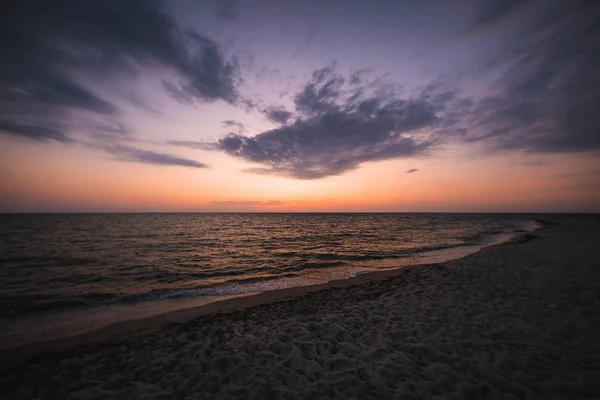 Красивий знімок пляжного берега під помаранчевим і блакитним небом на заході сонця — стокове фото