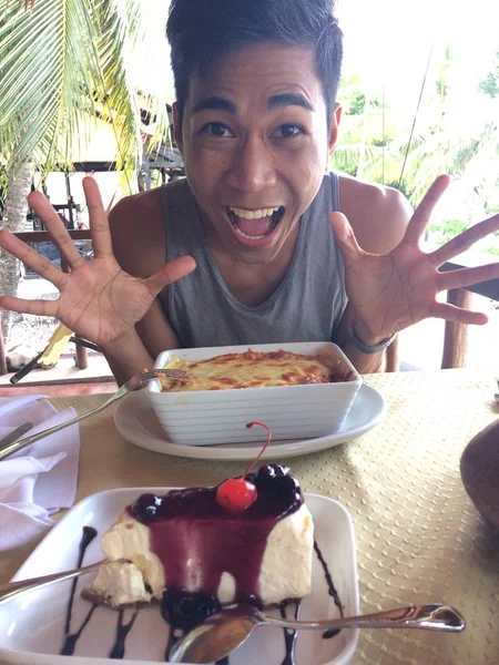 Tiro vertical de un macho feliz en una mesa con comida y postre —  Fotos de Stock