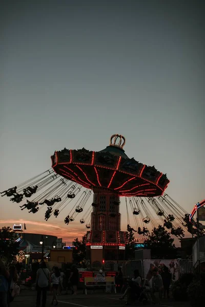 夜间在游乐园骑旋转木马的人的垂直镜头 — 图库照片