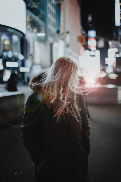 Selektive Nahaufnahme einer jungen blonden Frau auf der Straße in der Nacht mit verschwommenem Hintergrund — Stockfoto