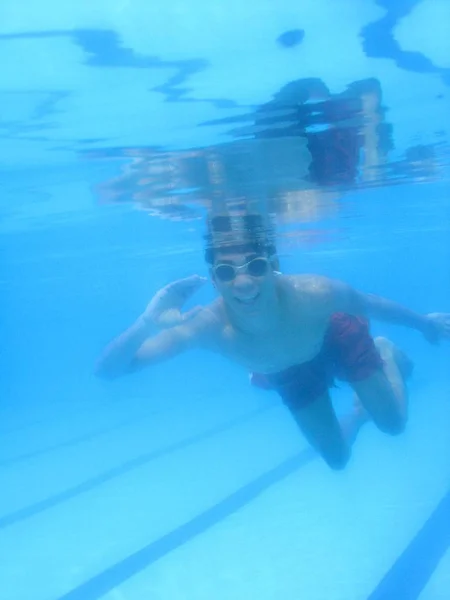 Вертикальный снимок человека в очках и красном купальнике под водой — стоковое фото