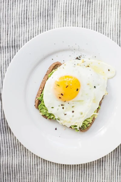 Fej feletti függőleges lövés egy tojás, saláta, és kenyér egy fehér tányéron — Stock Fotó