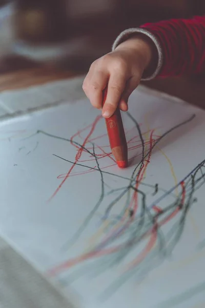 Kind tekening op een wit papiertje met een kleurpotlood in de kleuterschool — Stockfoto