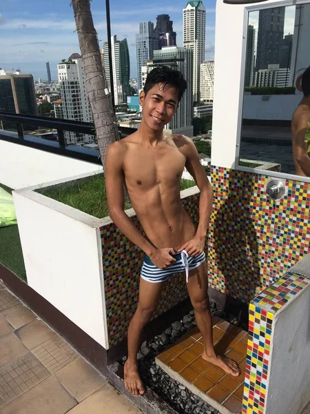 Tiro vertical de un macho con un traje de baño parado en un puesto de ducha al aire libre —  Fotos de Stock