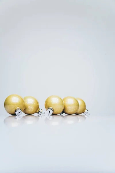 Tiro vertical de ornamentos de Natal coloridos de ouro em uma superfície branca — Fotografia de Stock