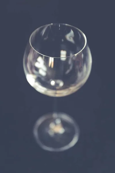 Selective closeup focus shot of a clear long-stemmed wine glass with a black background