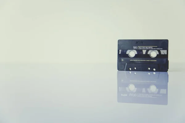 Black cassette tape with the reflection on white surface