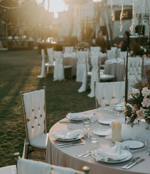 White reception table setting outdoors decorated with flowers and candles with a blurred background — Stock Photo, Image