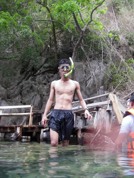 Tiro vertical de un macho caminando en el agua con snorkel cerca de los árboles — Foto de Stock