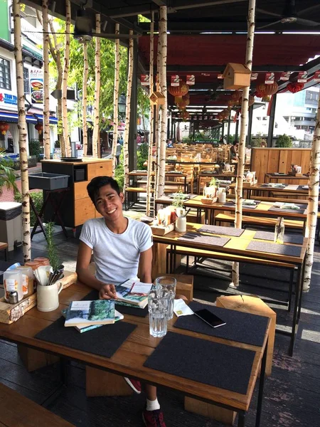 Tiro vertical de un macho sentado en una mesa en un café al aire libre — Foto de Stock