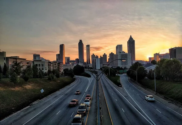 日落时分，美丽的高楼大厦和高速公路的宽阔景象，在五彩斑斓的天空下停放着汽车 — 图库照片