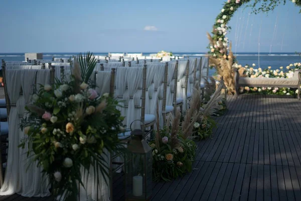 Выстрел из украшенных арочных и белых стульев для свадебной церемонии у водоема — стоковое фото