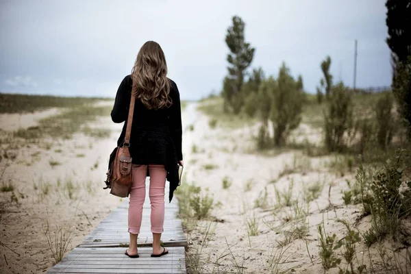 Weibchen steht auf einem Holzweg inmitten einer sandigen Fläche mit verschwommenem Hintergrund — Stockfoto