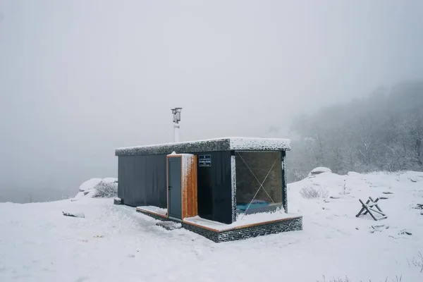Zamknij ujęcie małego domku na zaśnieżonej górze z zamglonym tłem — Zdjęcie stockowe