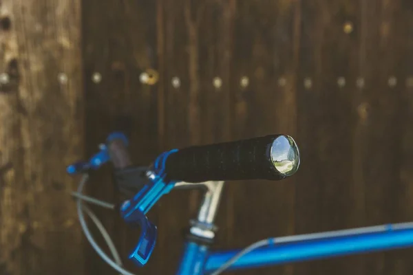 Κοντινό πλάνο εστίασης ενός μπλε ποδηλάτου ακουμπισμένο σε έναν ξύλινο τοίχο — Φωτογραφία Αρχείου