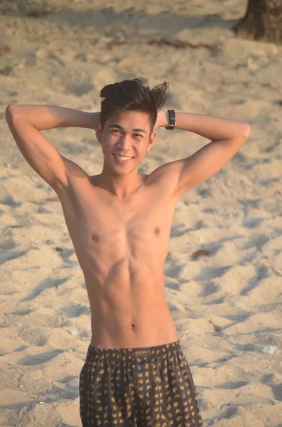 Colpo selettivo verticale di un maschio che indossa un costume da bagno sullo sfondo della spiaggia sabbiosa — Foto Stock