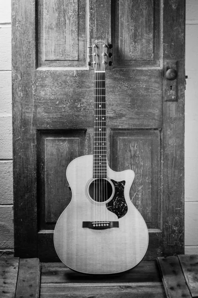 나무로 된 문에 기대어 있는 음향 기타의 아름다운 회색 칼 사진 — 스톡 사진