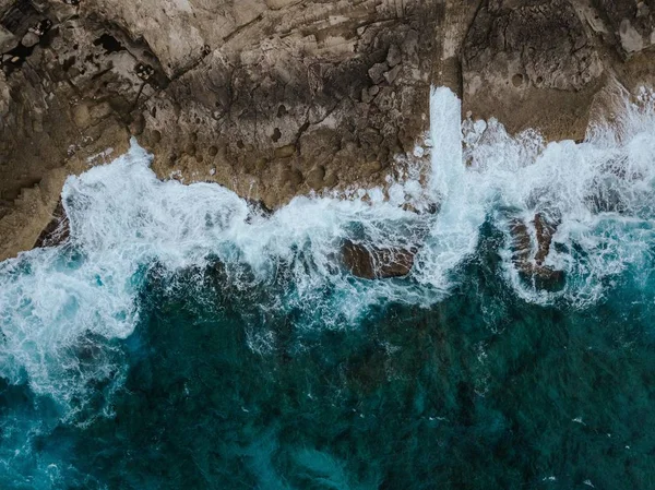 Foto aerea aerea aerea delle belle scogliere dell'oceano e l'acqua spruzzi su di loro — Foto Stock