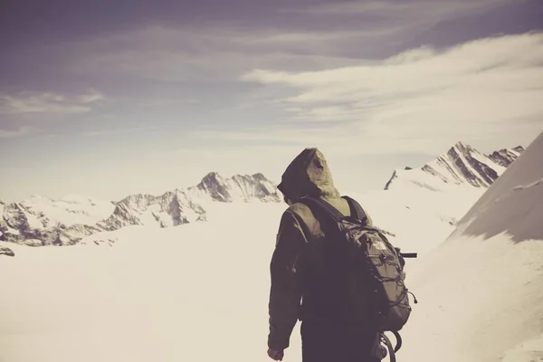 A shot of a person in the mountains covered in snow under the beautiful cloudy sky