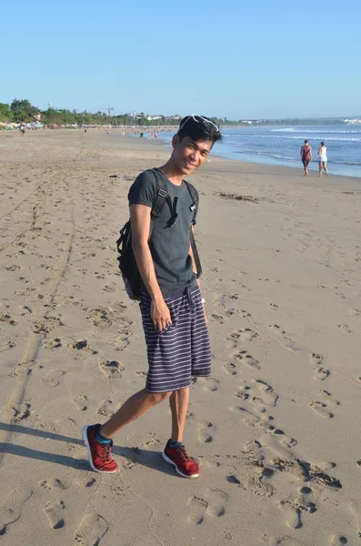 모래가 많은 해변에서 있는, 선글라스를 쓰고 회색의 검은 셔츠를 입은 한 남자의 수직 사진 — 스톡 사진