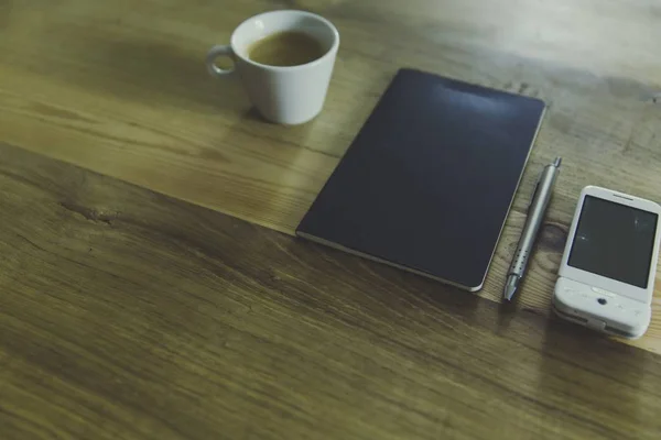 Plan grand angle d'un carnet avec un stylo argenté, une tasse de café et un téléphone portable blanc — Photo