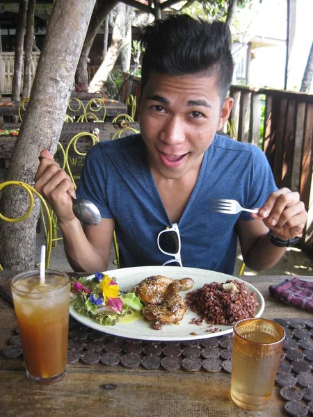 Foto vertical de un macho que come alas de pollo y alforfón cocinado. —  Fotos de Stock