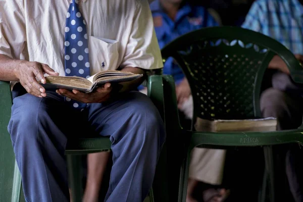 背景がぼやけている本を読んで椅子に座っている高齢者の男性の終わりのショット — ストック写真