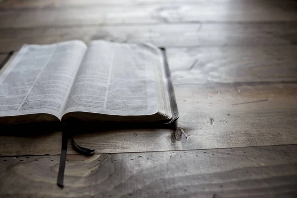 Fechar tiro de bíblia sagrada em uma mesa de madeira com um fundo borrado — Fotografia de Stock