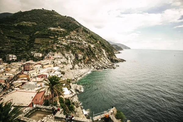 Hög vinkel skott av en liten stad med hus nära havet och ett högt grönt berg — Stockfoto