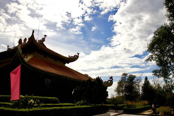 Vue large d'un toit de temple à Cu Chi, Vietnam avec un drapeau devant et un ciel bleu en arrière-plan — Photo