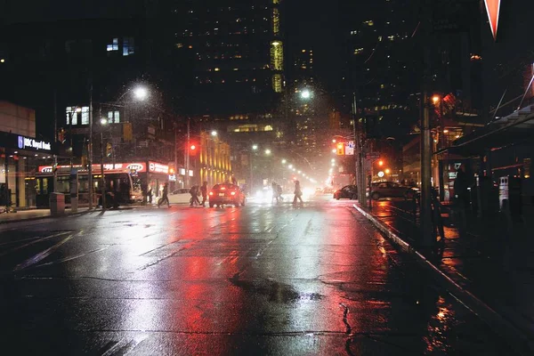 Mooi shot van mensen en auto 's op een natte straat tijdens een regenachtige nacht — Stockfoto
