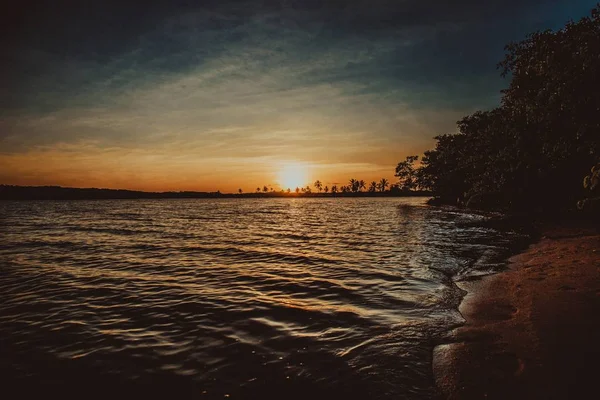Οριζόντια λήψη γαλήνιου υδάτινου σώματος κοντά στην ακτή κατά τη διάρκεια του ηλιοβασιλέματος — Φωτογραφία Αρχείου