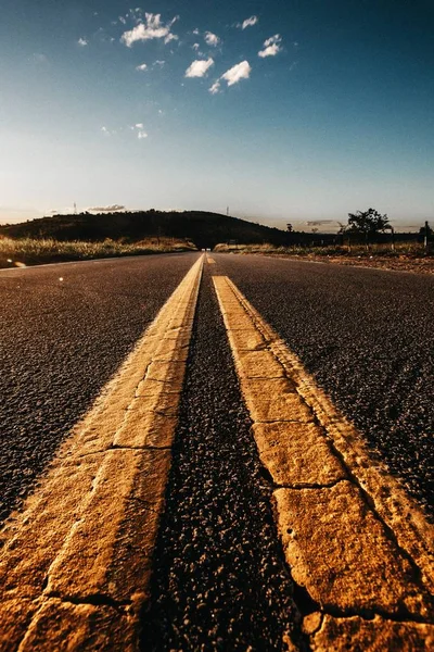 Scatto verticale di una strada vuota con linee gialle sopra — Foto Stock