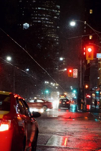 Verticale opname van een straat tijdens de nacht met auto 's en verkeerslichten terwijl sneeuw — Stockfoto