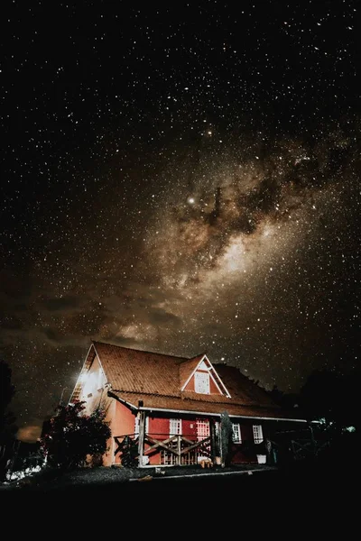 星空の下で赤木造の家の垂直ショット — ストック写真