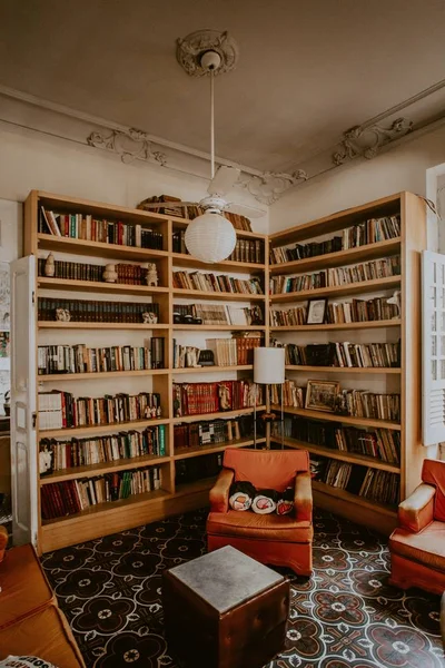 Scatto verticale di una stanza d'epoca con librerie e poltrone arancioni — Foto Stock