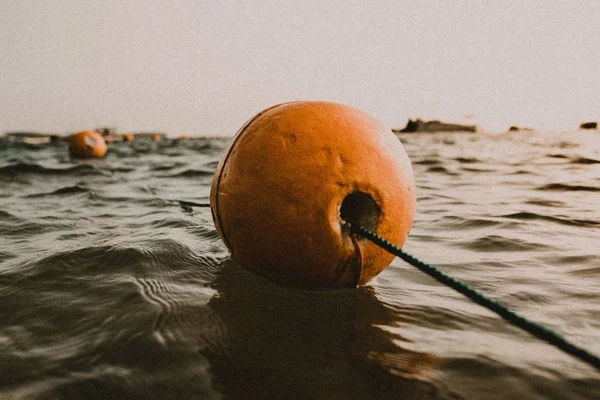 Närbild skott av en orange boj i samband med ett rep på en lugn vattensamling — Stockfoto