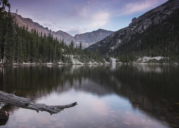 Paisagem tiro de um lago calmo com árvores e montanhas no fundo — Fotografia de Stock