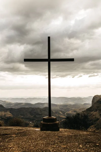 Colpo verticale di una croce cristiana su una scogliera durante nuvoloso — Foto Stock
