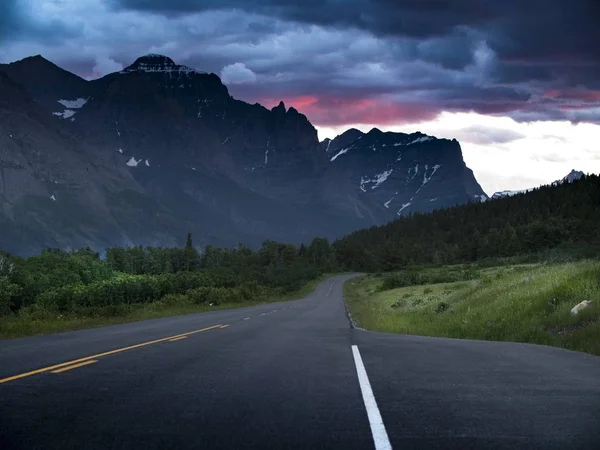 Fotografía horizontal de una carretera que atraviesa los campos con montañas al fondo —  Fotos de Stock