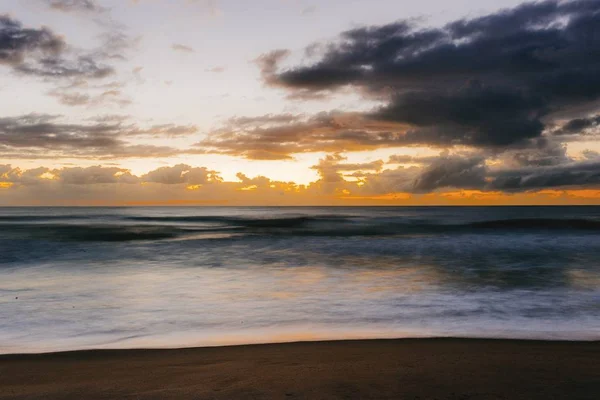 Горизонтальный снимок пляжа с безмятежным водоёмом во время заката — стоковое фото