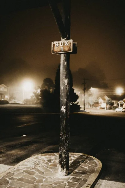 Vertical shot of a black pole with a sign that says "BOX 1" during the night in a town — Stock Photo, Image
