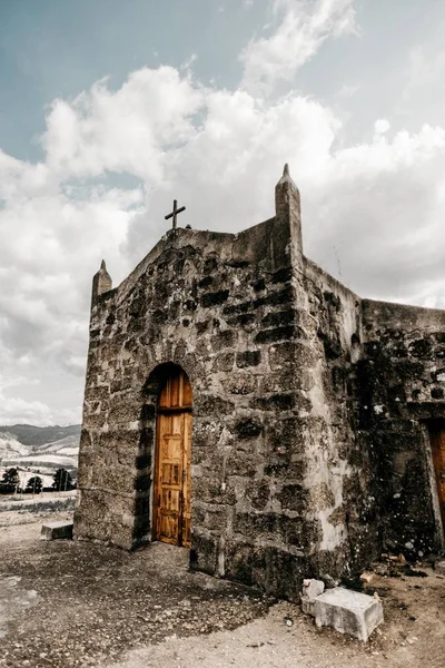 Scatto verticale di una vecchia chiesa con muri logori sulla cima di una rupe — Foto Stock